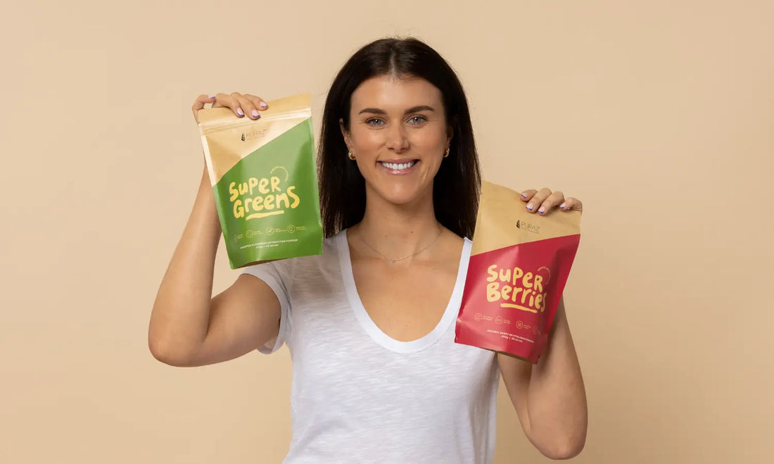 Puraz superfood powders with greens, berries, shaker and smoothie on a bright kitchen bench