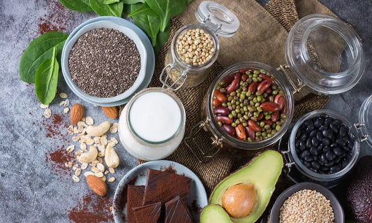 Healthy natural nails beside eggs, kiwifruit, vegetables and other foods for nail growth support