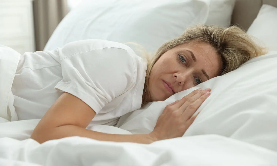 Midlife woman adjusting lightweight bedding during a calm menopause night routine