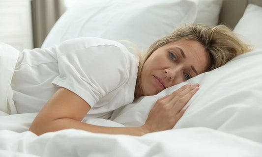 Midlife woman adjusting lightweight bedding during a calm menopause night routine