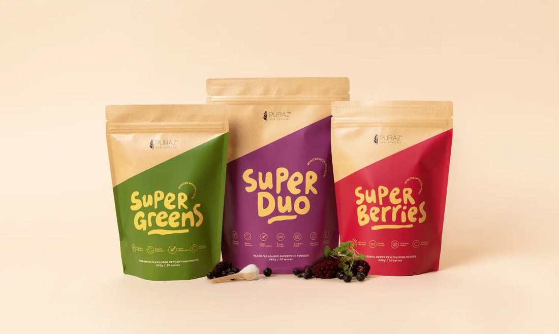 Three balanced superfood smoothies with greens, berries, collagen powder, fruit, yoghurt and oats on a bright kitchen bench.